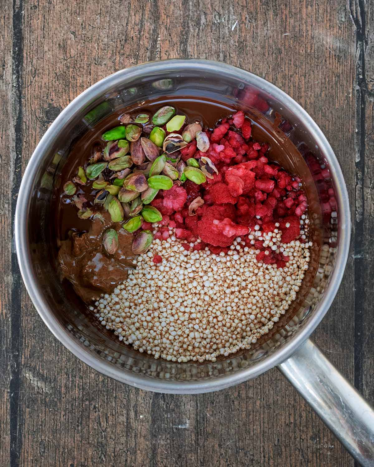 Puffed quinoa, nut butter, raspberries and pistachios added to the melted chocolate.