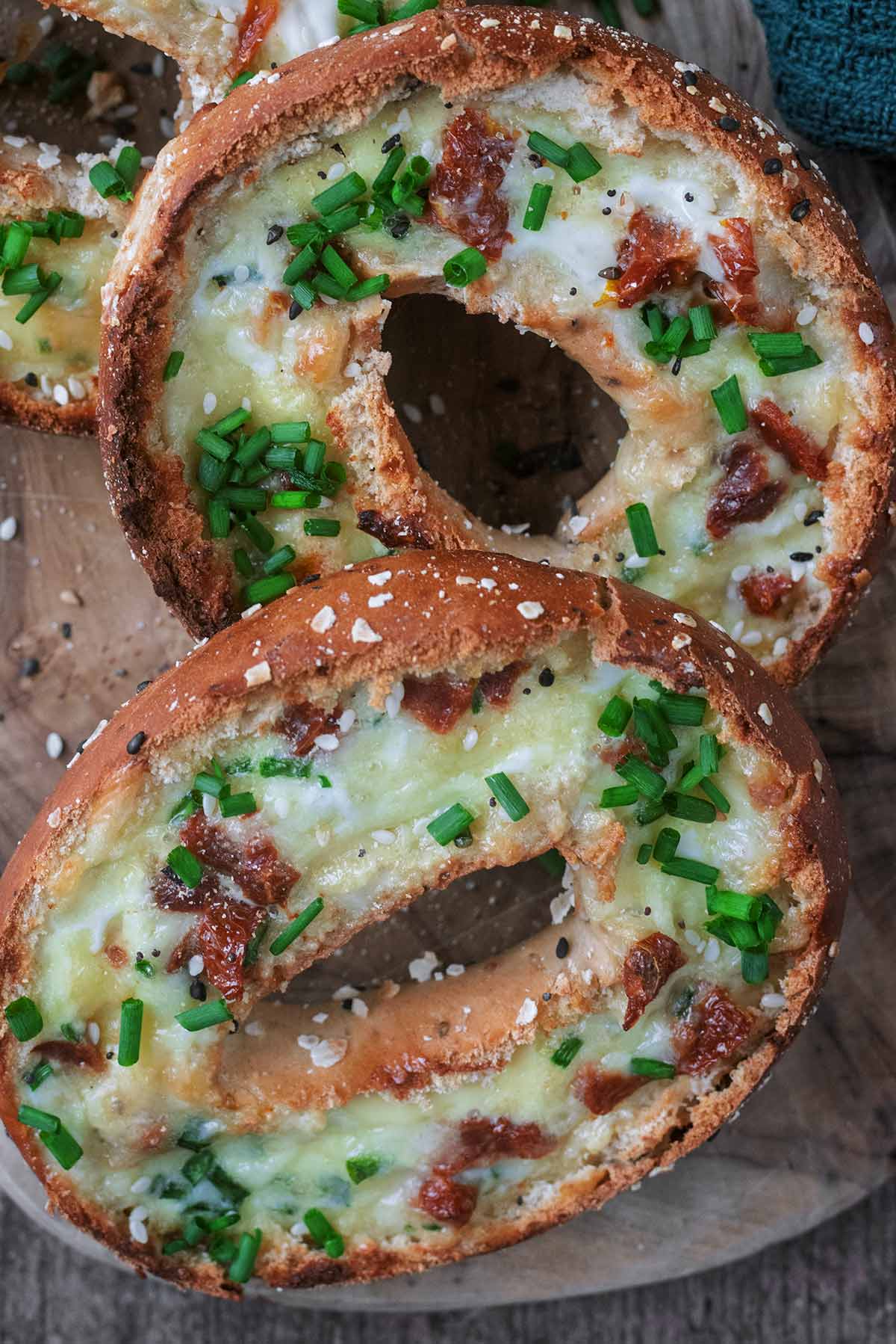 Two stuffed bagels topped with fresh chives.