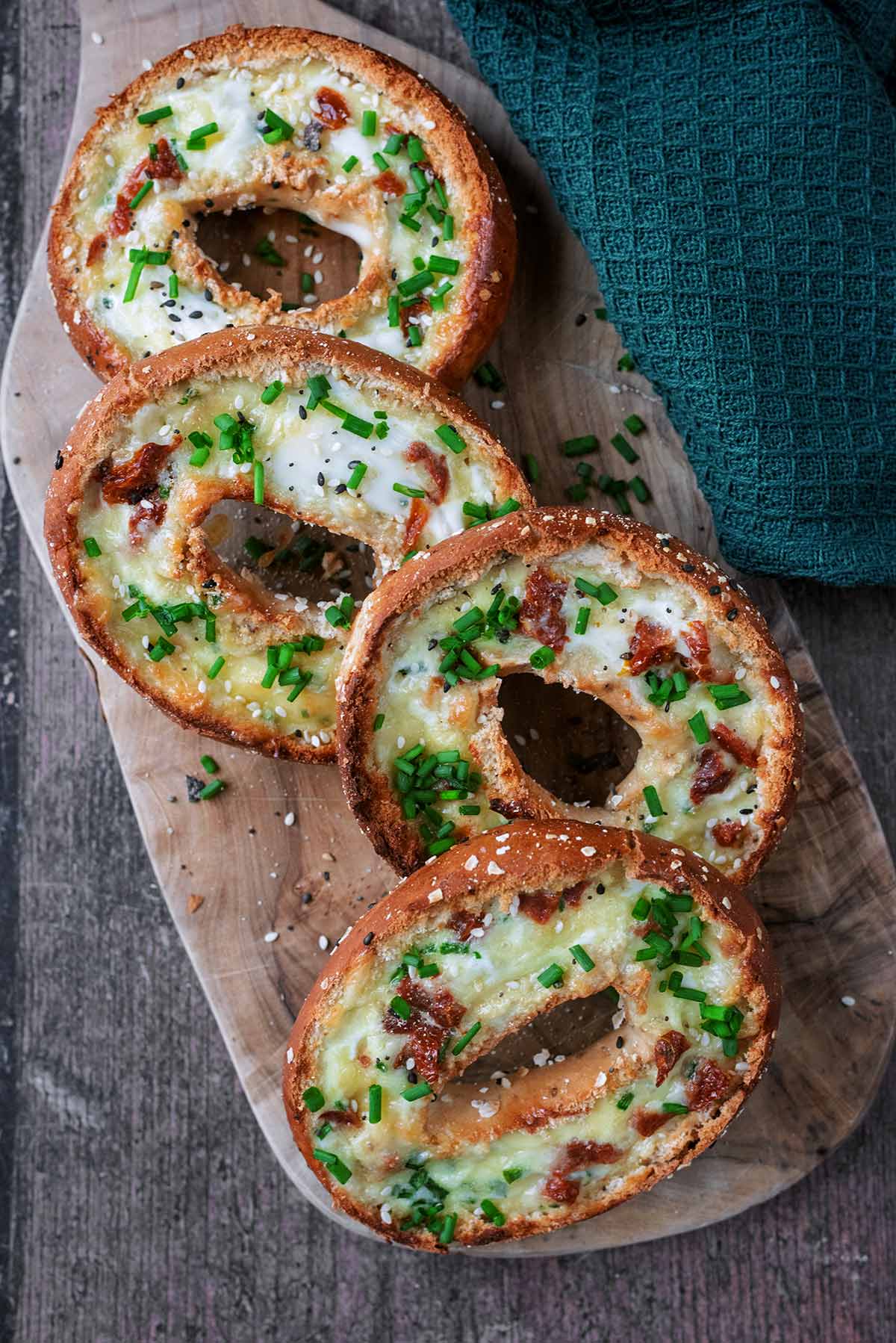 Four sliced open bagels filled with a cooked egg mixture.