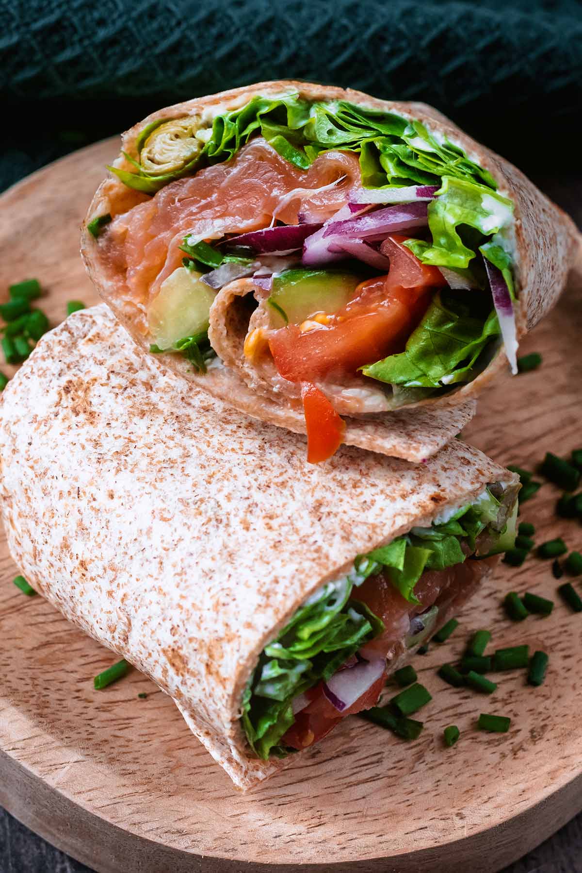 The insides of a salmon wrap showing lettuce, salmon, onion, tomato and cucumber.