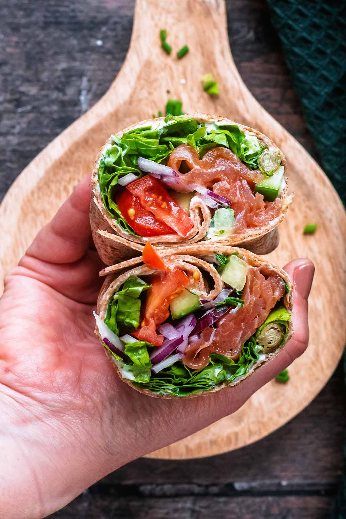 A hand holding two halves of a sliced open wrap.