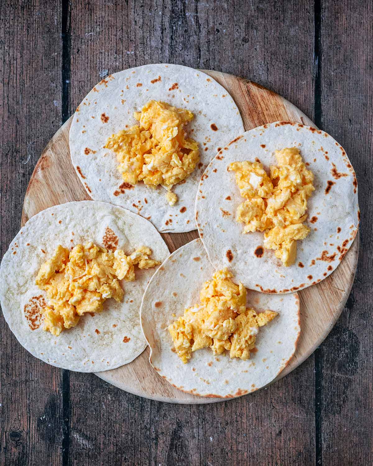 Four mini tortillas with scrambled egg on them.