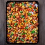Chicken sausage tray bake on a wooden surface.