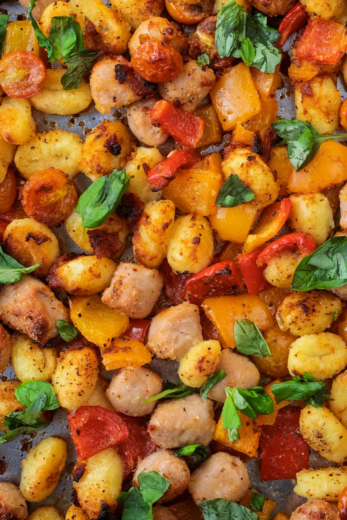 Cooked gnocchi, sausage meat and vegetables topped with fresh basil leaves.