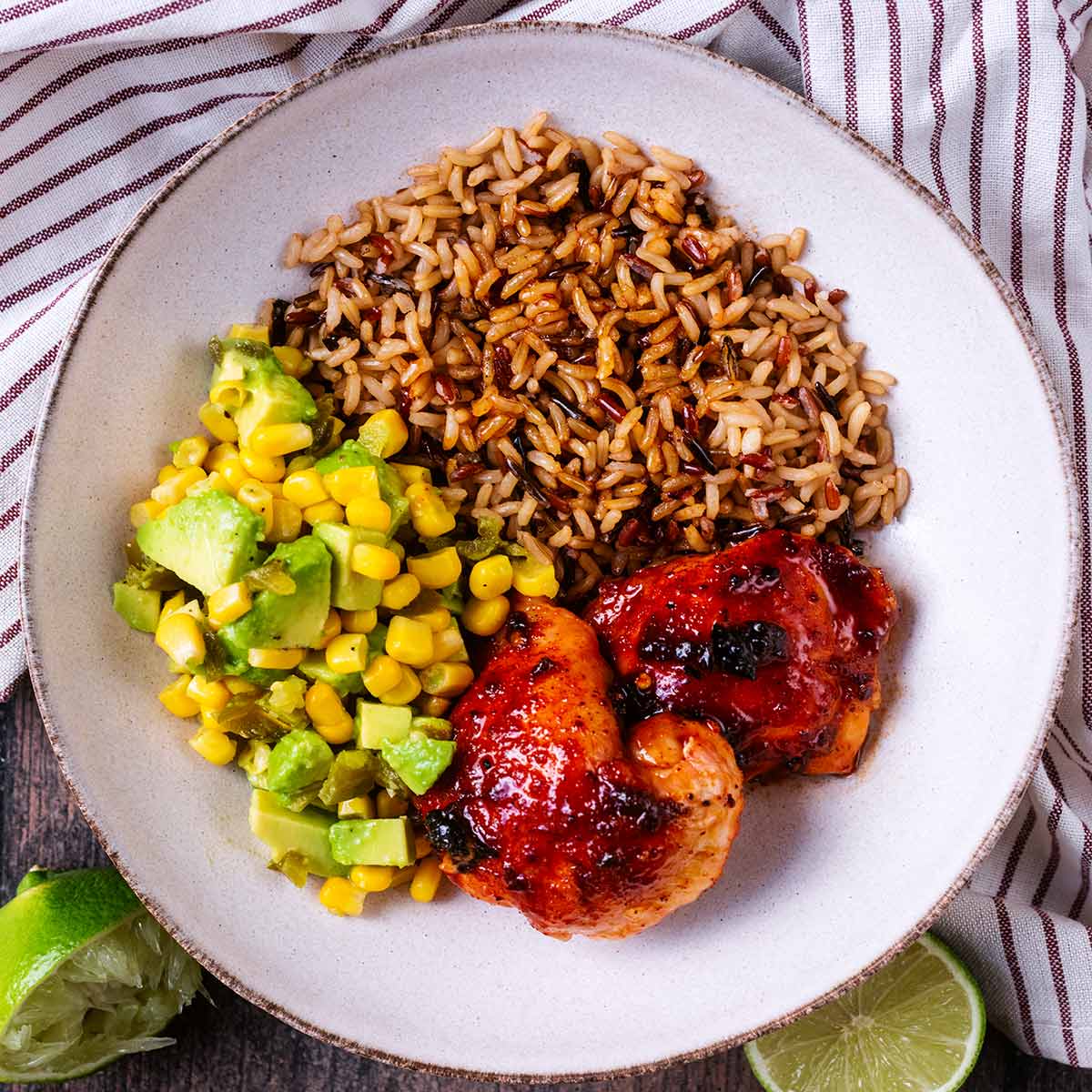 Chilli honey baked chicken thighs, brown rice and avocado salsa in a bowl.