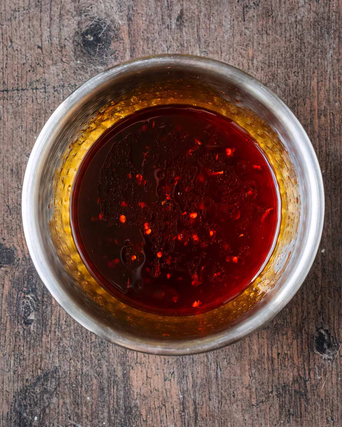 A mixing bowl containing a mixture of honey, chilli sauce and soy sauce.