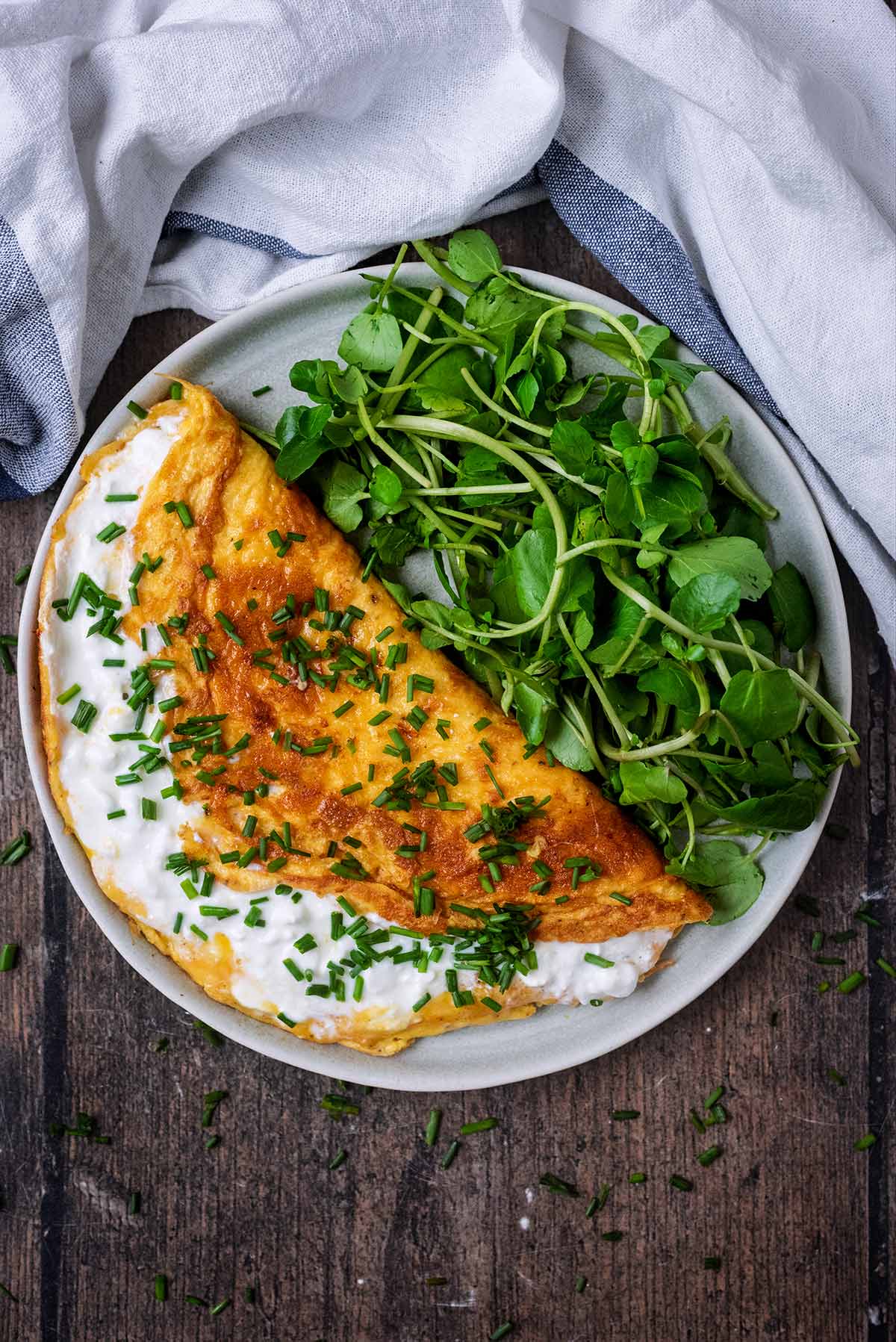 A cheese omelette on a plate with watercress.
