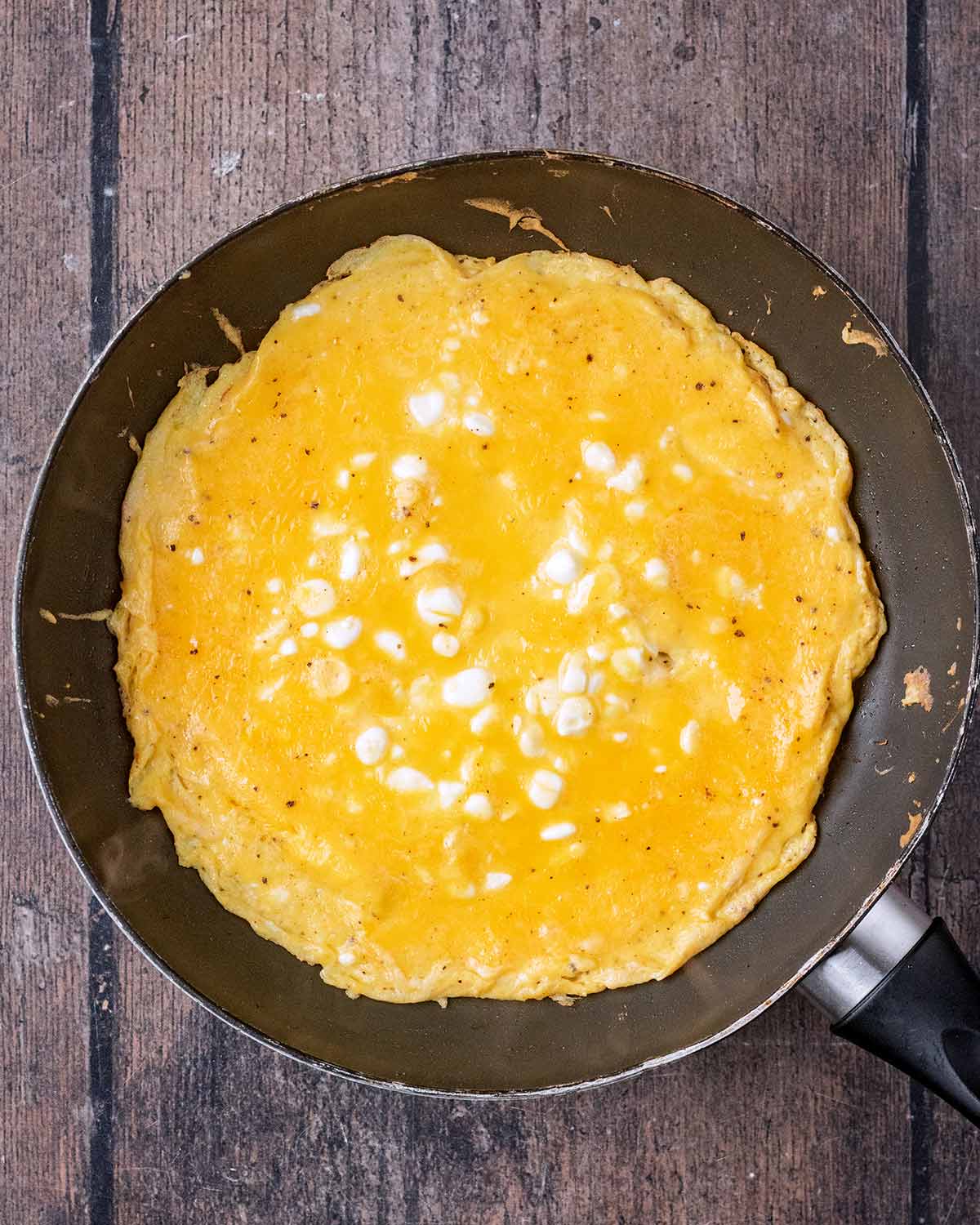 Whisked eggs and cottage cheese cooking in a frying pan.
