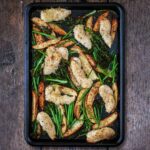Crispy parmesan chicken traybake on a wooden surface.