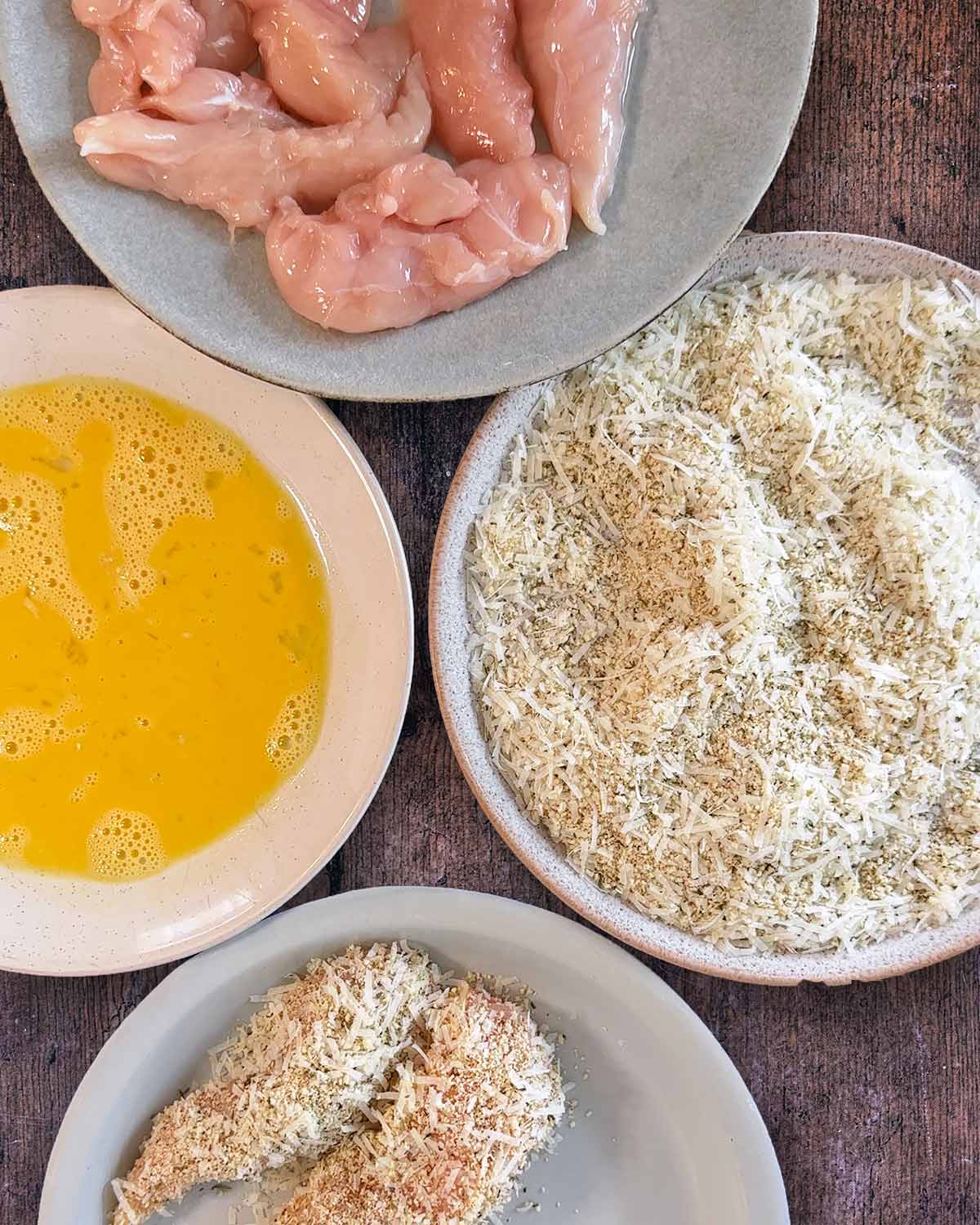 Plate of plain chicken tenders, breadcrumb mixture, whisked egg and coated chicken.