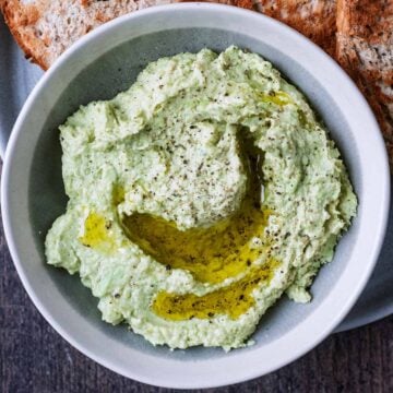 A bowl of edamame hummus swirled with olive oil.