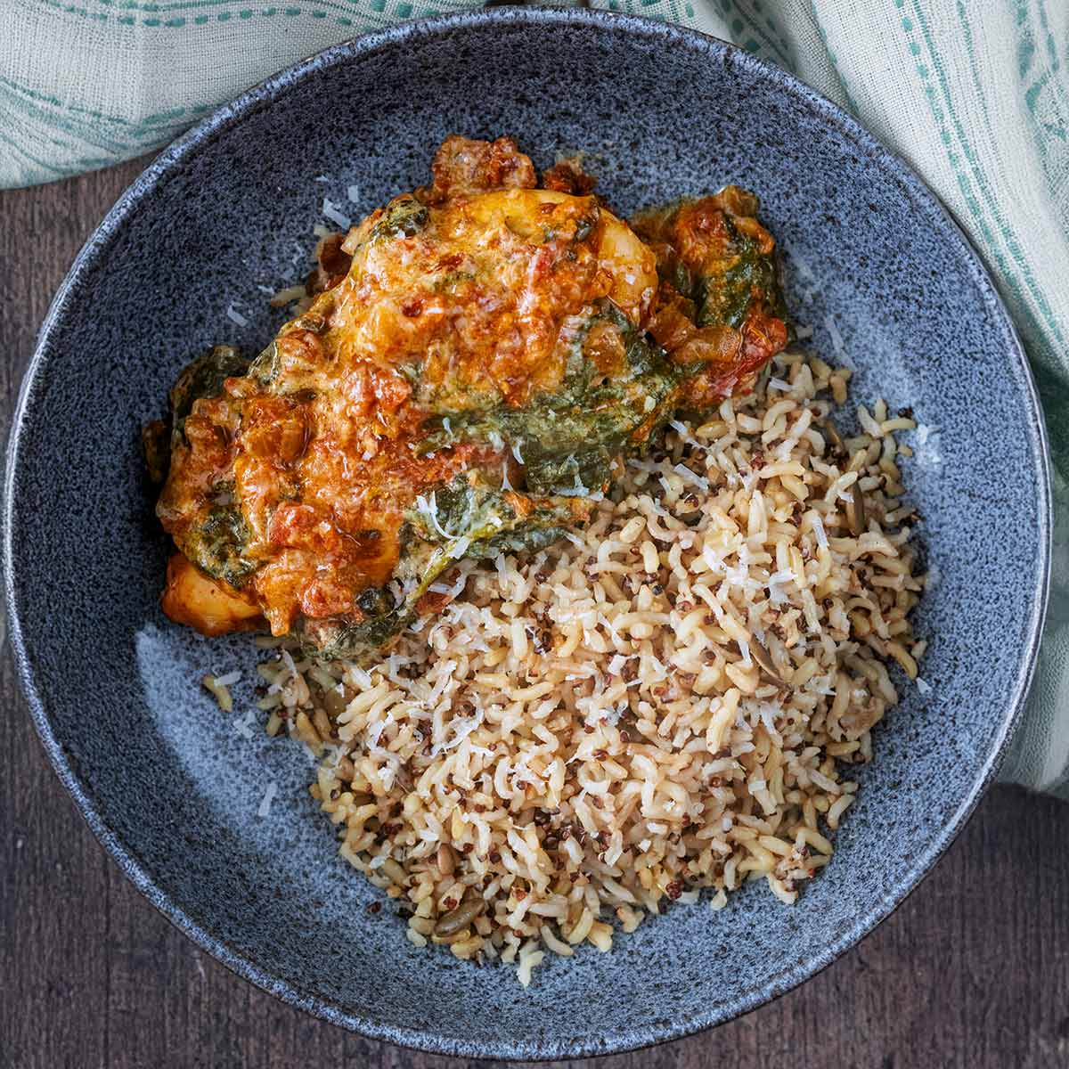 Slow cooker pesto chicken in a bowl with cooked rice.
