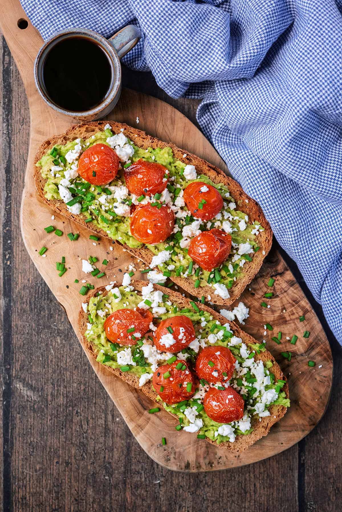 Avocado on toast topped with roasted tomatoes, crumbled feta na d chopped chives.