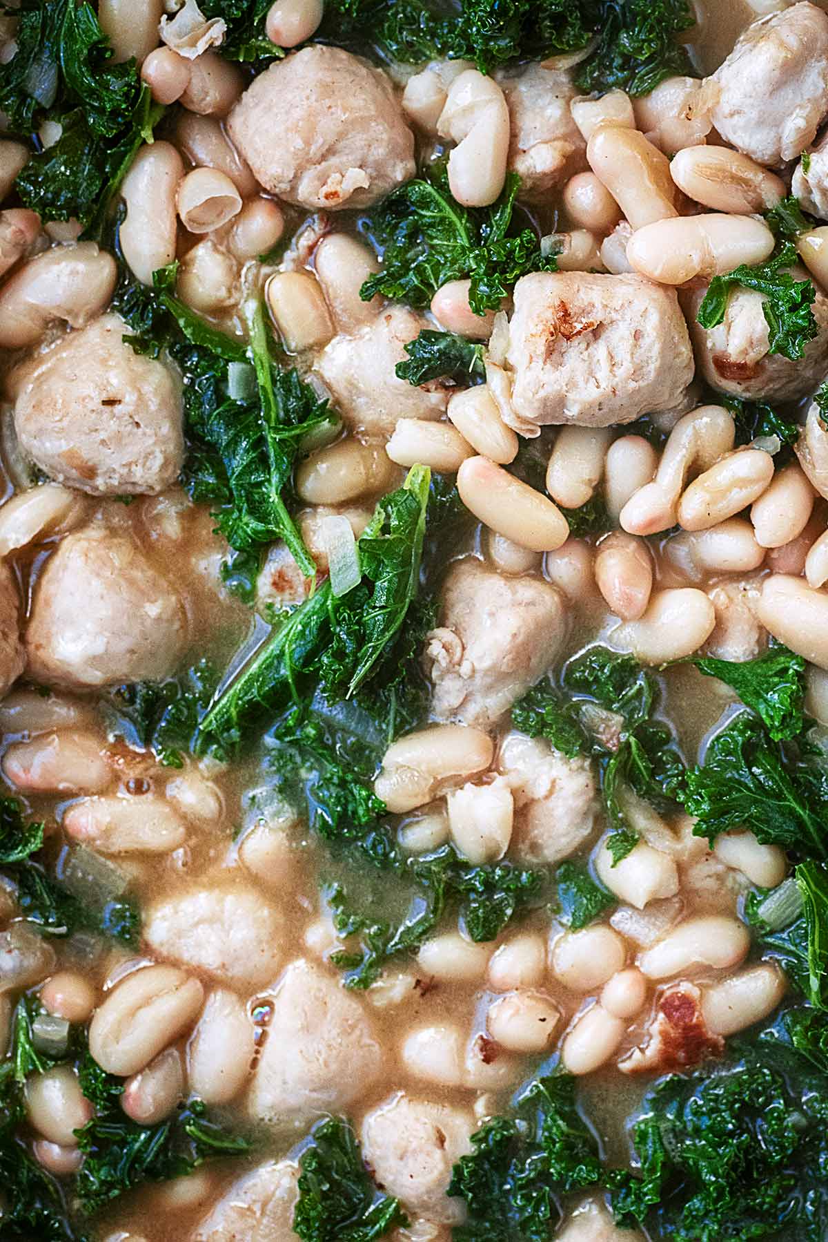 Cooked kale, cannellini beans and chunks of sausage in a creamy sauce.