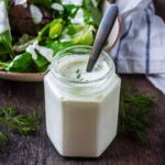 A jar of Greek yogurt salad dressing with a spoon in it.