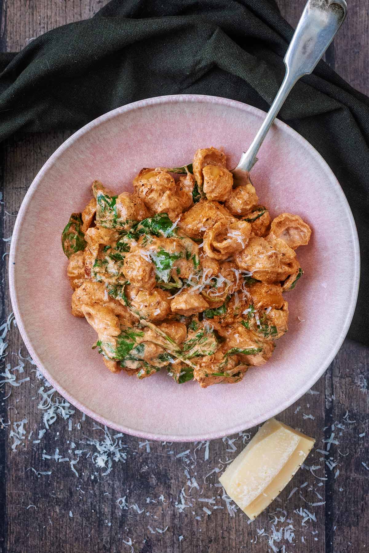 A bowl of chicken pasta in a creamy sauce with a fork in it.