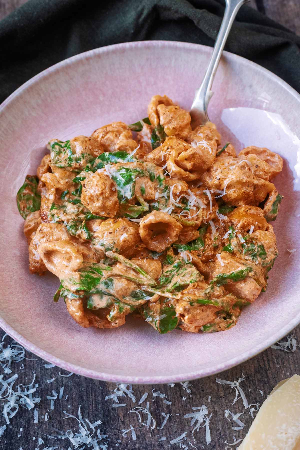 A bowl of marry me chicken in front of a green towel.