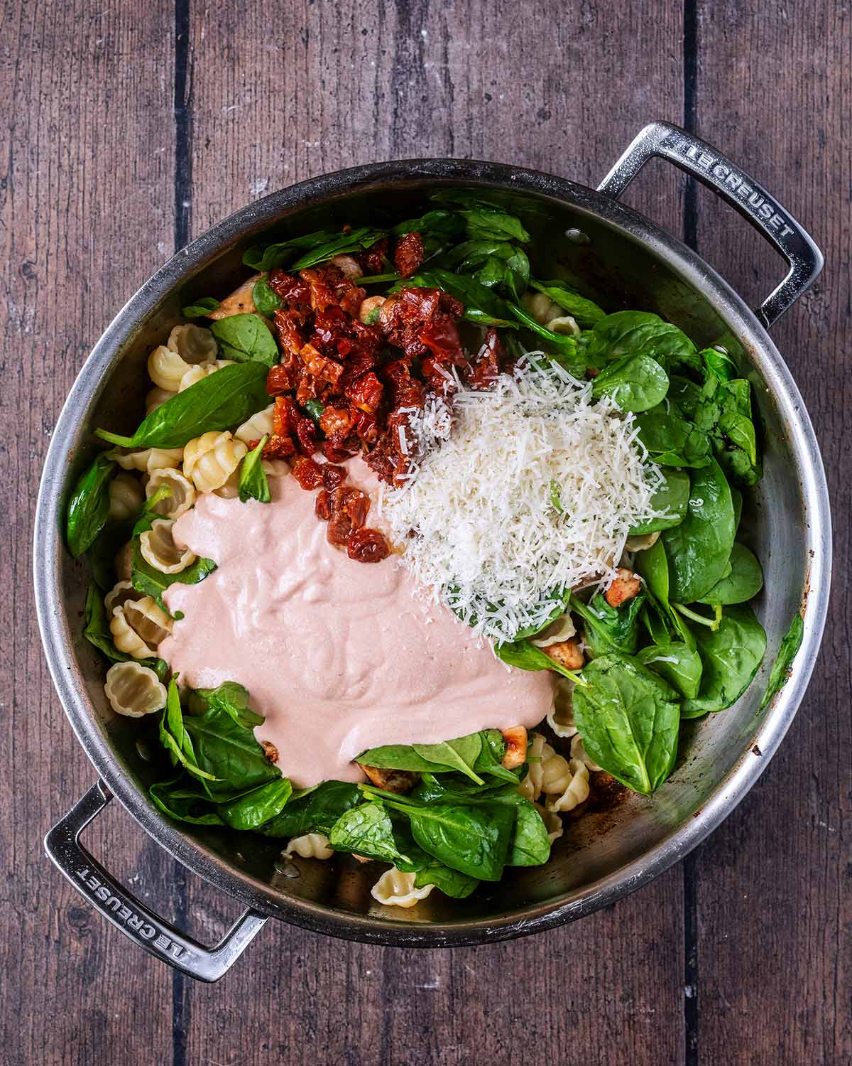 Sun-dried tomatoes, grated Parmesan and the sauce added to the pan.