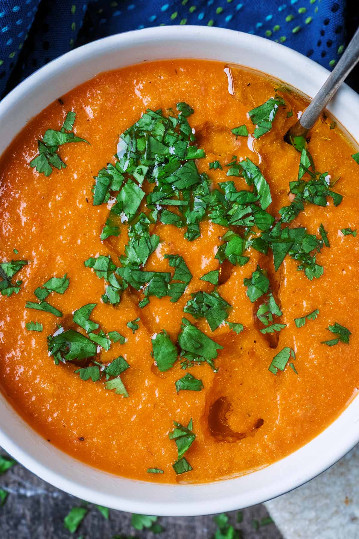 Tomato soup with a drizzle of oil and chopped herbs on top of it.