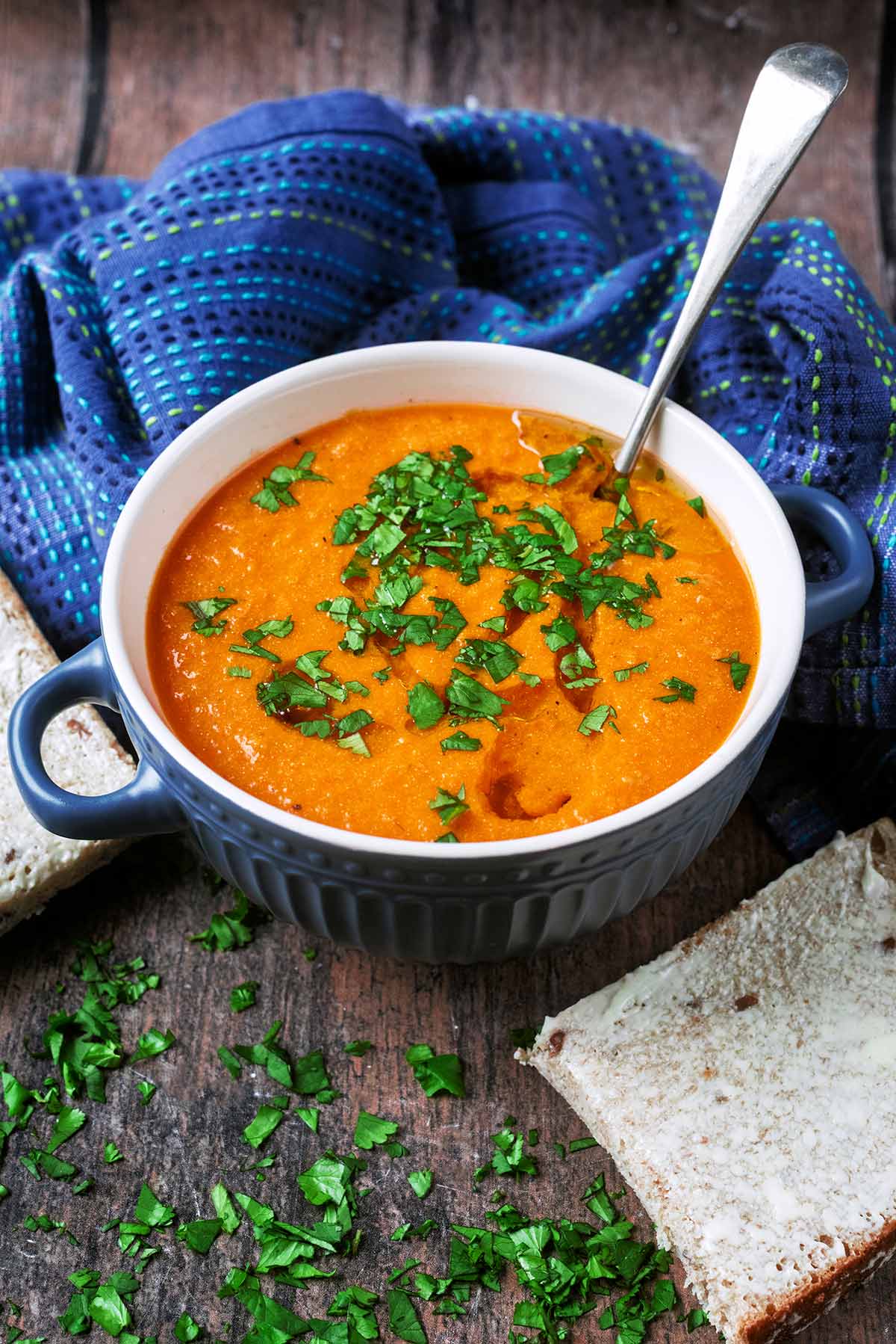 A bowl of tomato soup in front of a blue towel.
