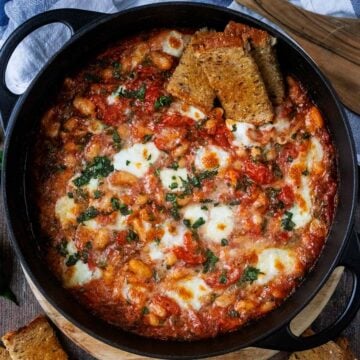 Cheesy white bean bake in a large round black pan.
