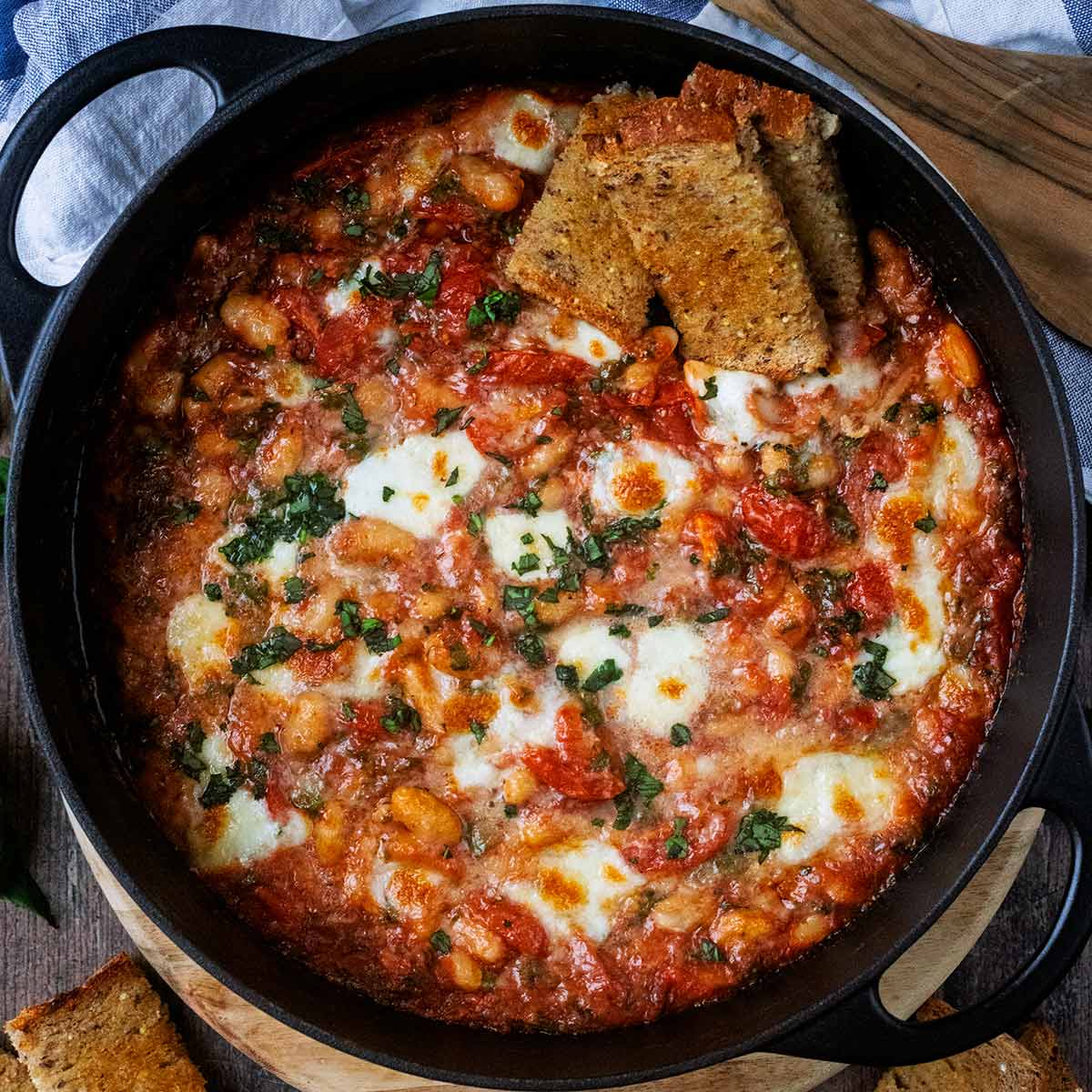 Cheesy white bean bake in a large round black pan.