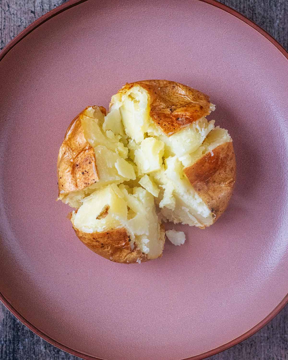 A baked potato cut open in a cross.