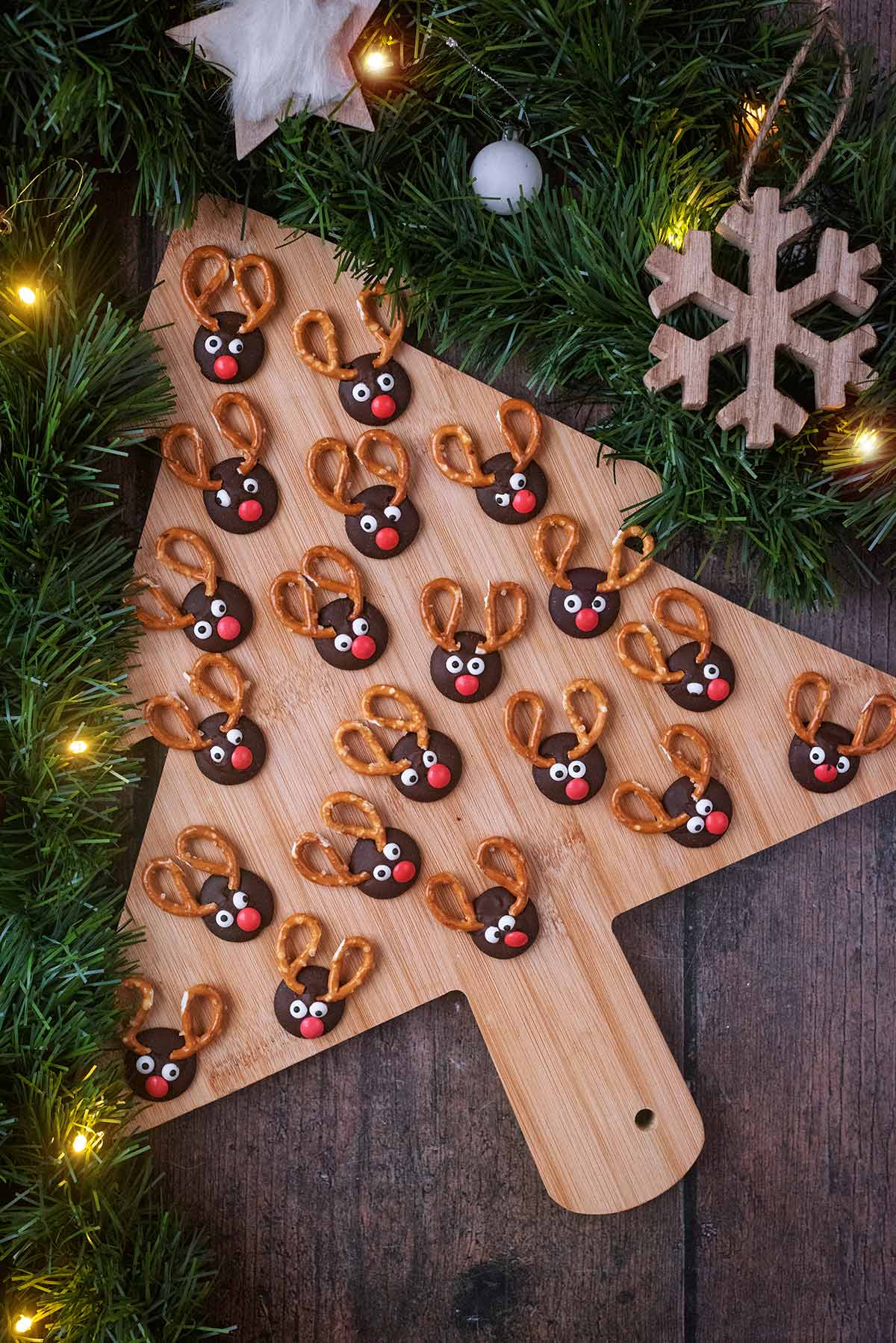 A Christmas tree shaped board covered in mini chocolate reindeer faces.