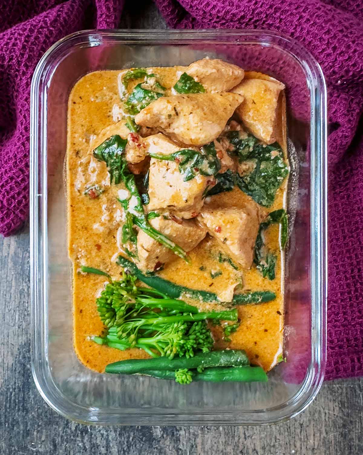 Leftover curry and broccoli in a glass storage container.