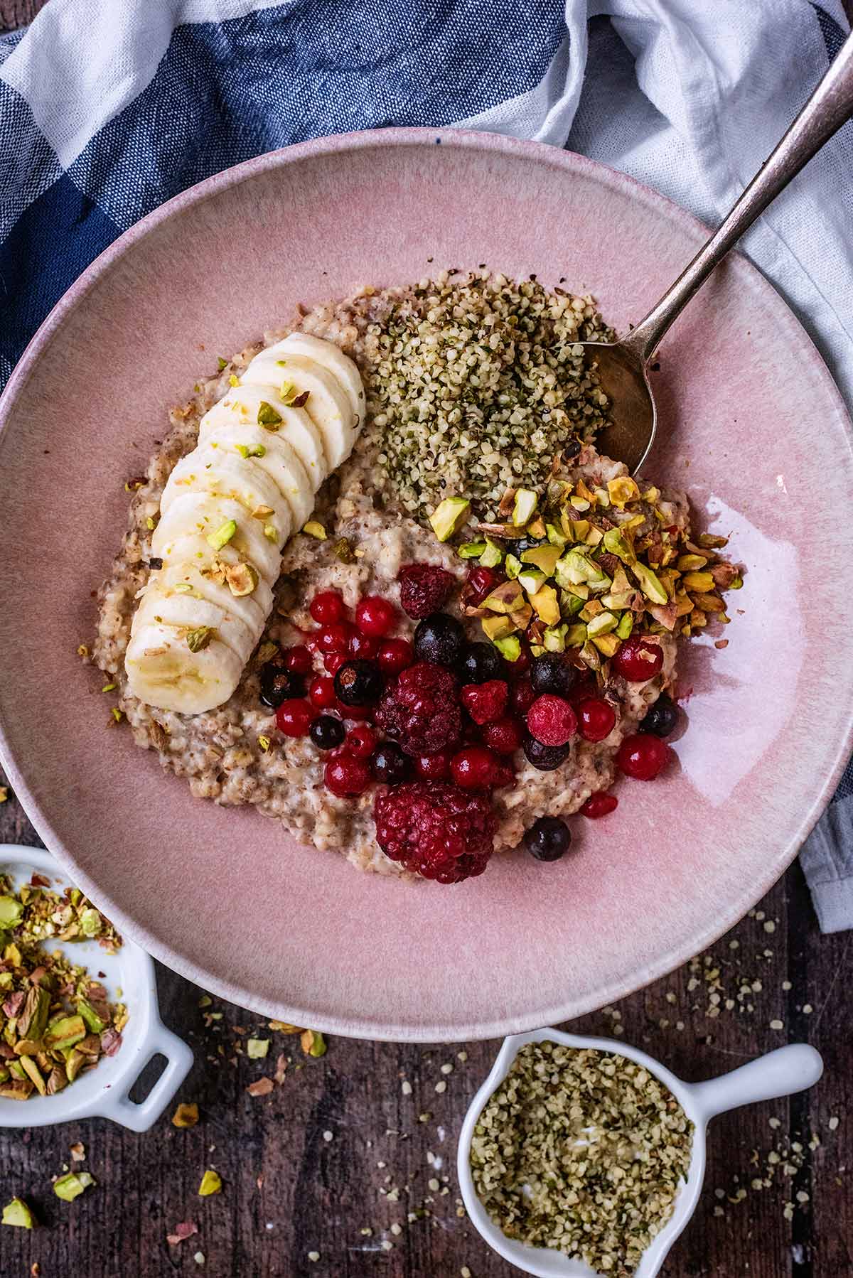 A pink bowl with fruit and seed topped porridge in it.