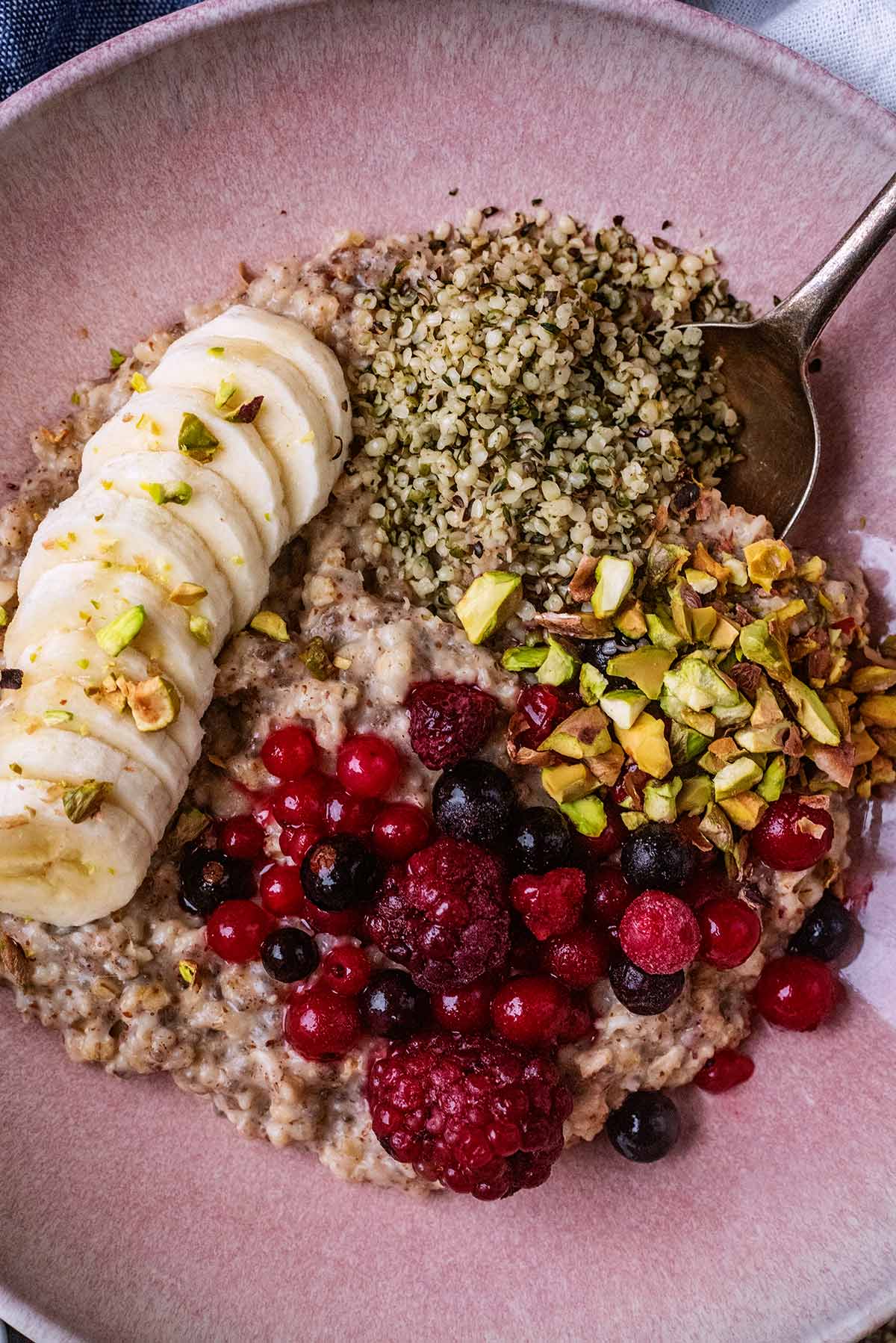 Sliced banana, berries and seeds on top of a portion of porridge.