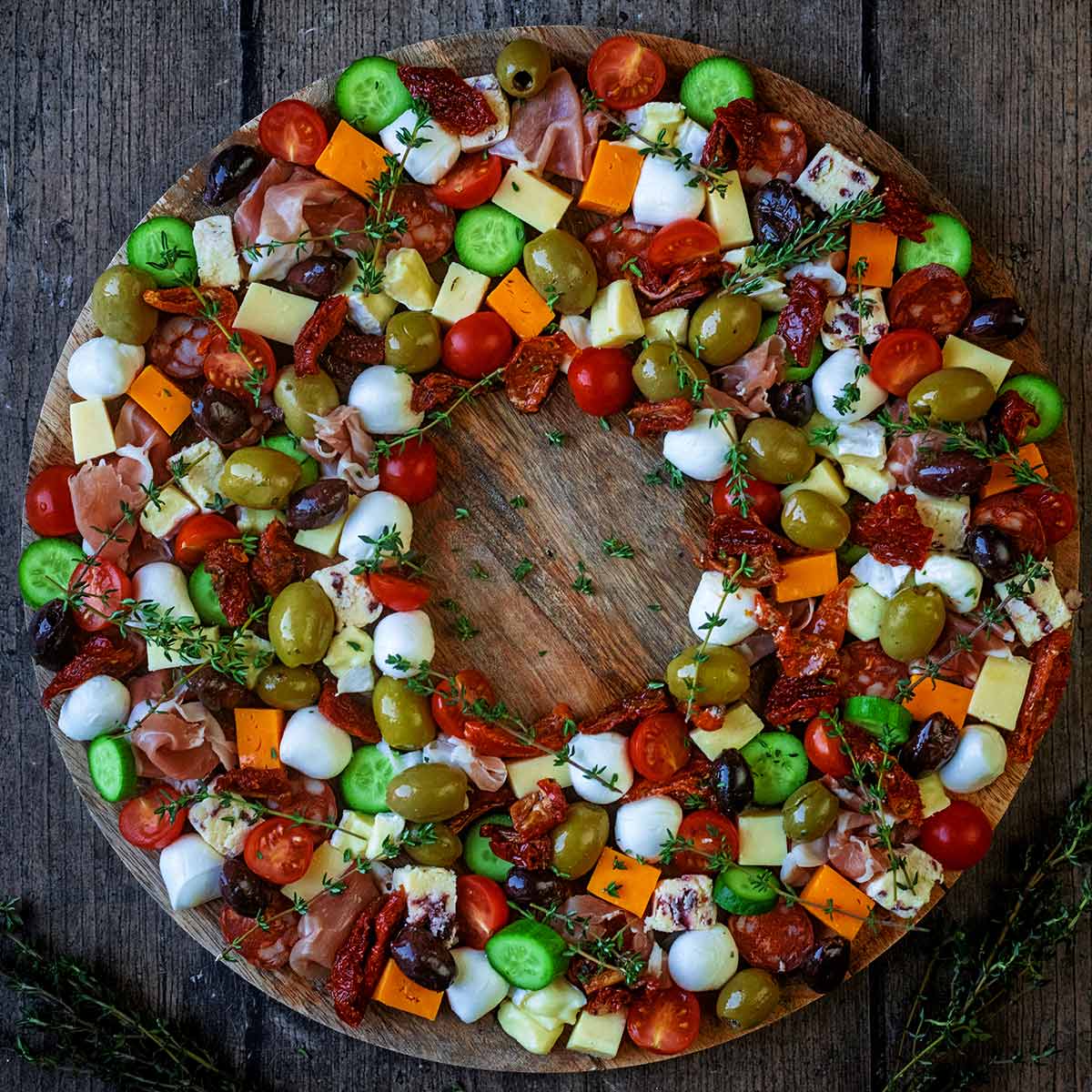 An antipasto wreath on a large round wooden board.