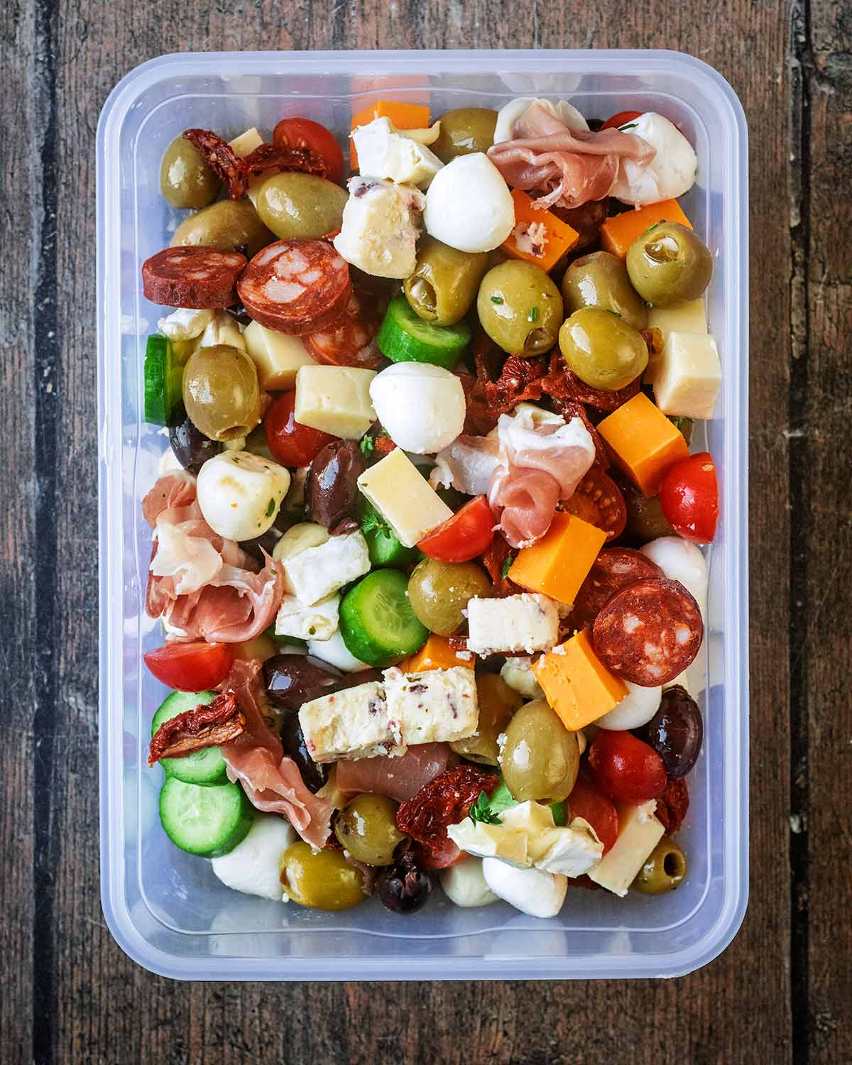 A rectangular tub with antipasto ingredients in it.