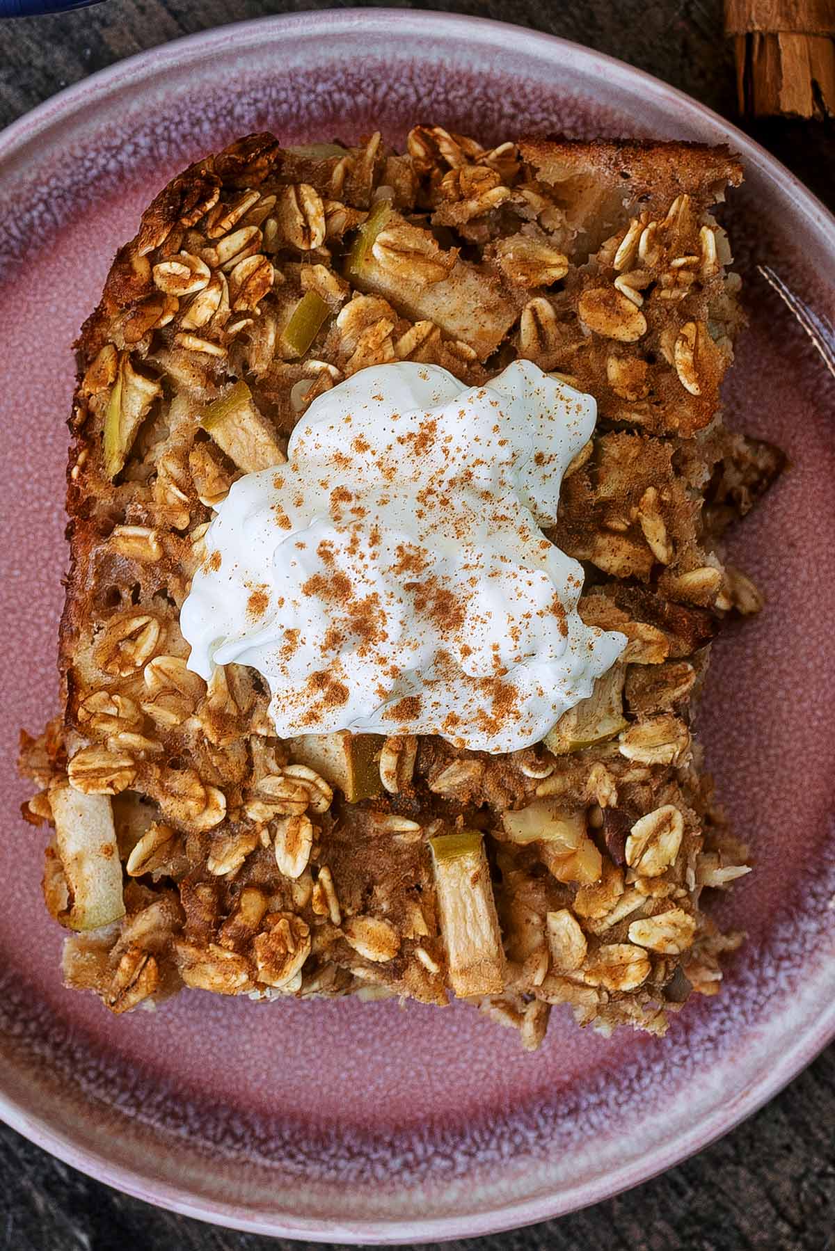 A slice of baked oats topped with a dollop of yogurt and some ground cinnamon.
