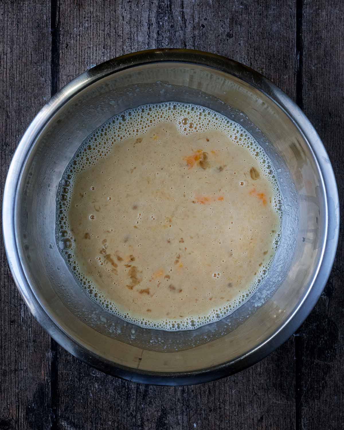 Whisked eggs, milk, maple syrup and apple sauce mixed in a bowl.