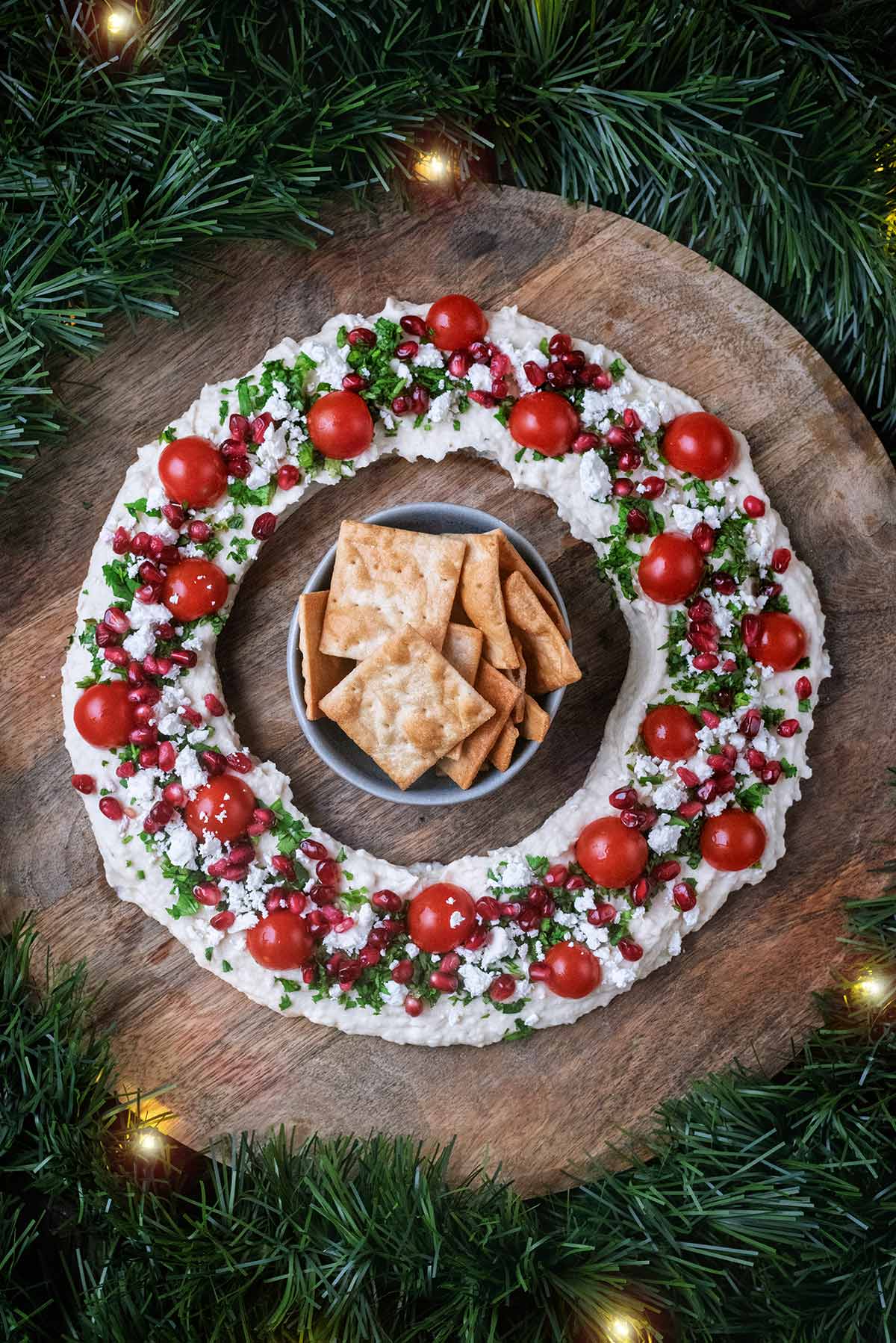 A wreath made from hummus, cherry tomatoes, pomegranate and herbs.