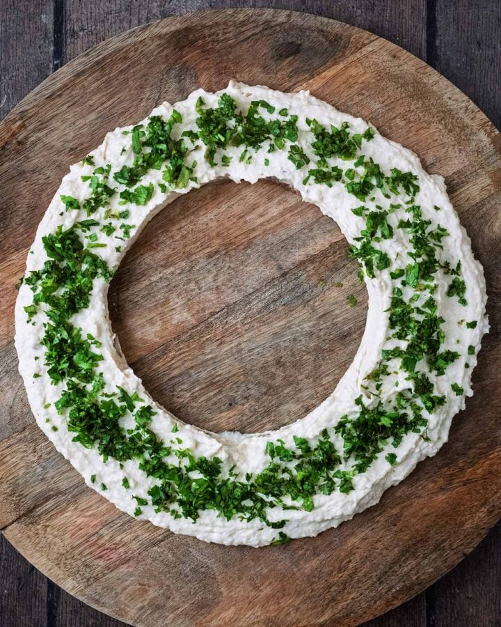 Chopped herbs scattered over a ring of hummus.