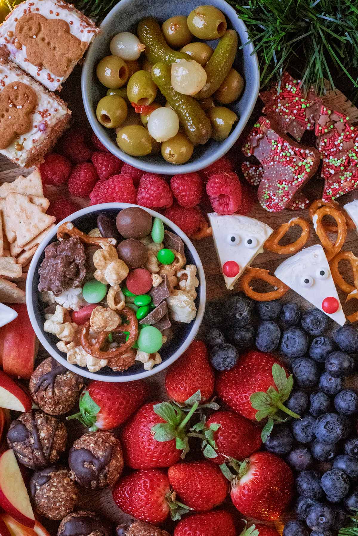 Bowls of Merry Mix and pickles surrounded by Christmas snacks.