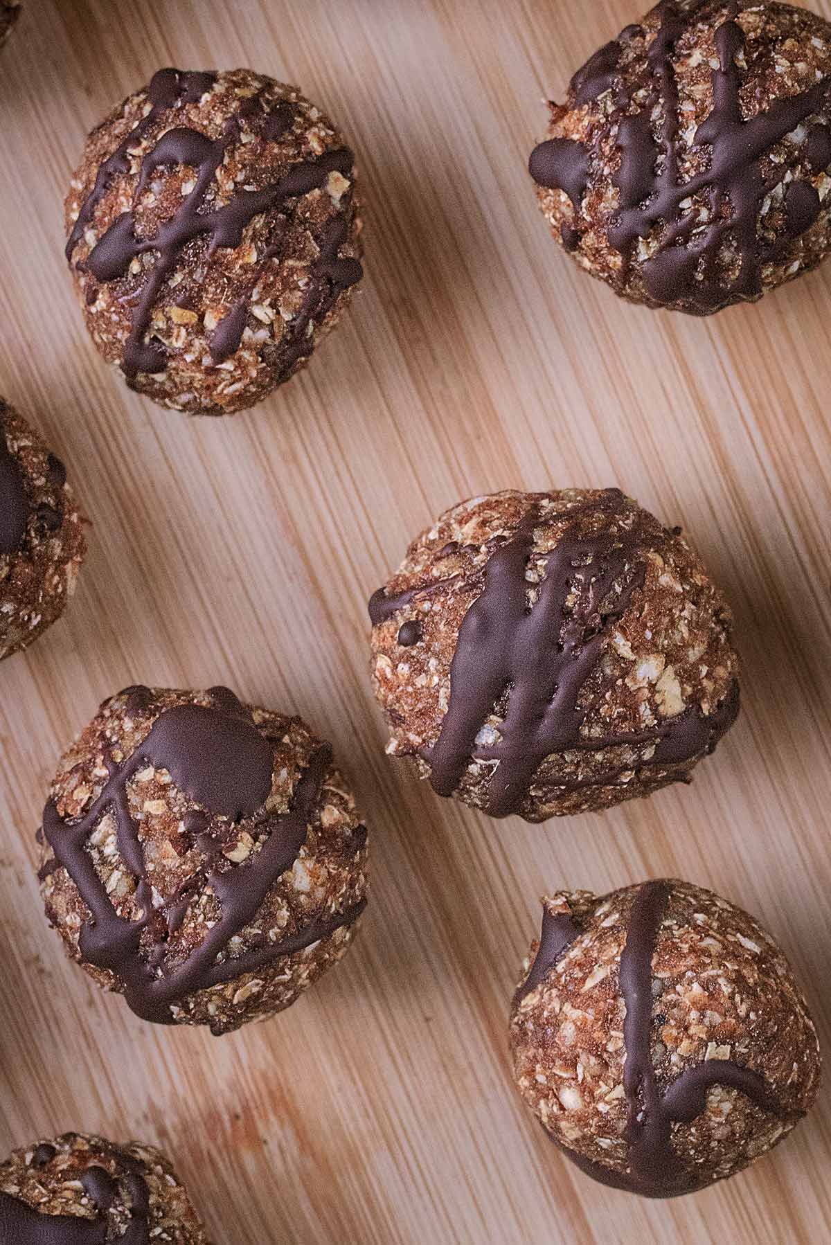Five energy balls with chocolate drizzled over them.