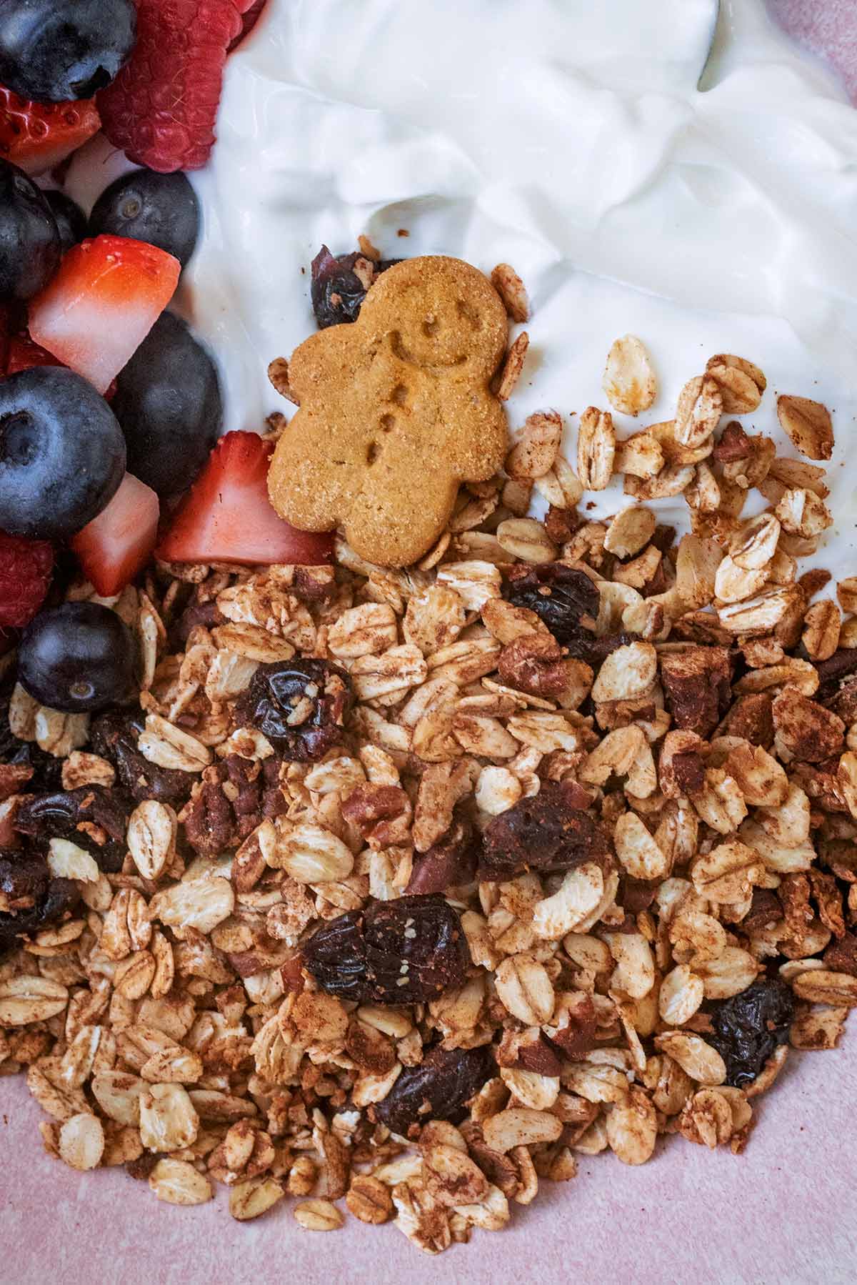 Granola and a small gingerbread person on top of some yogurt.
