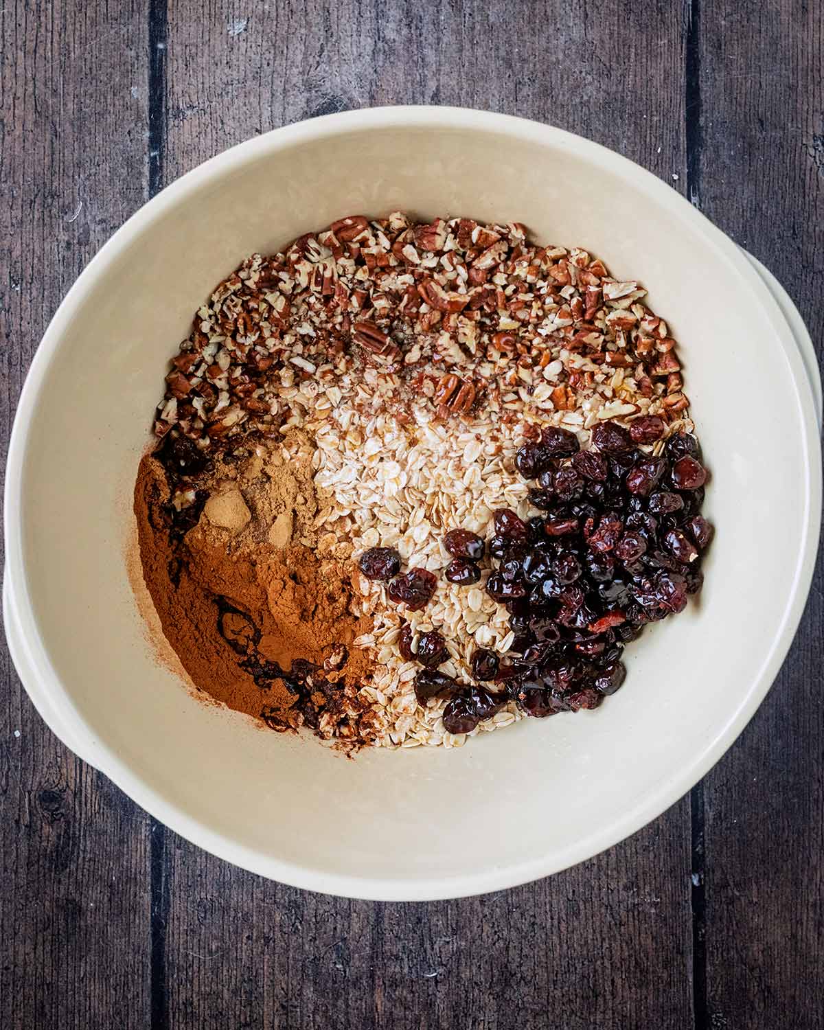 Oats, nuts, cranberries, spices and maple syrup in a large mixing bowl.