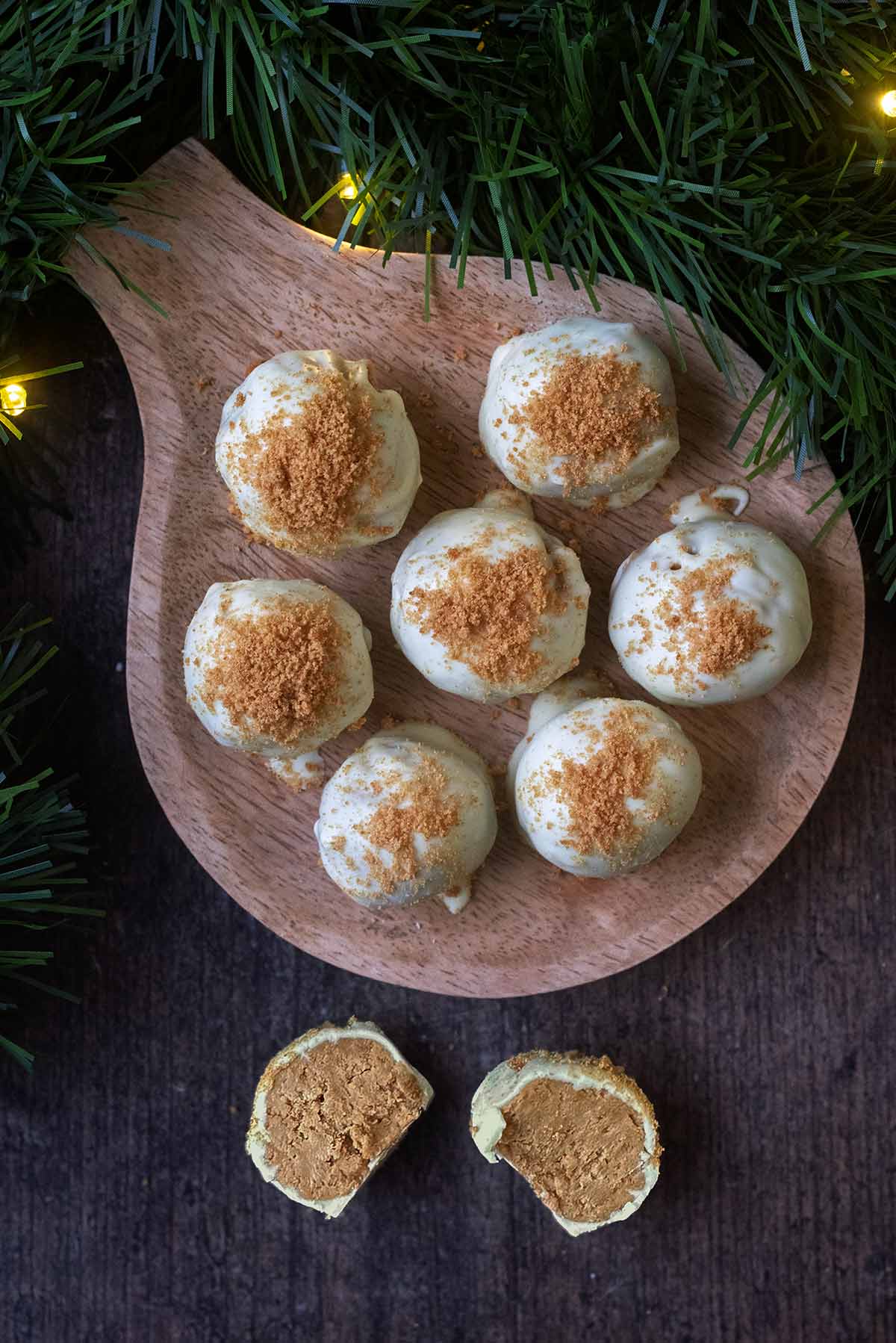 Seven white chocolate coated truffles on a board with another truffle cut open.
