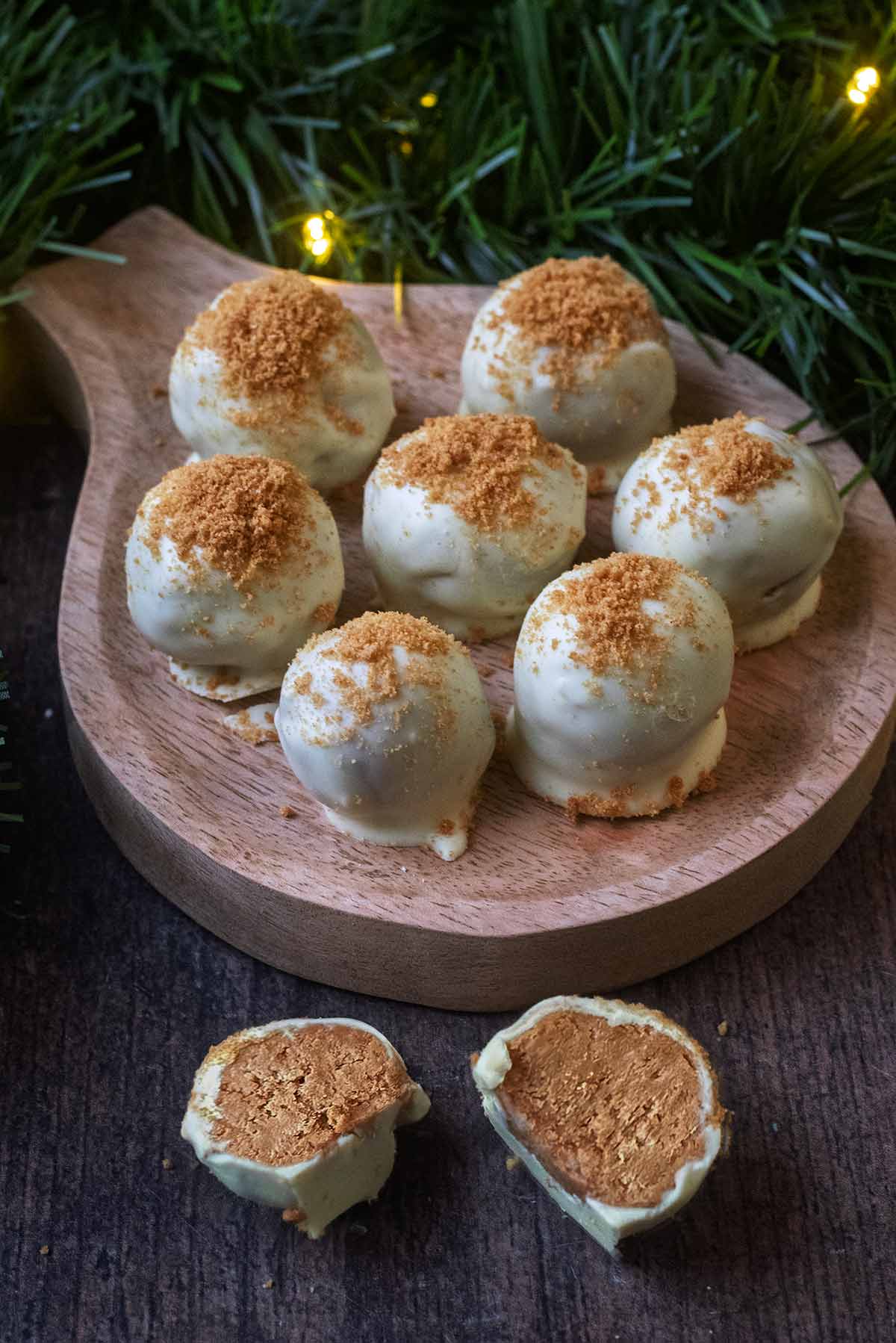 Gingerbread truffles on a small rount serving board in front of a green Christmas garland.