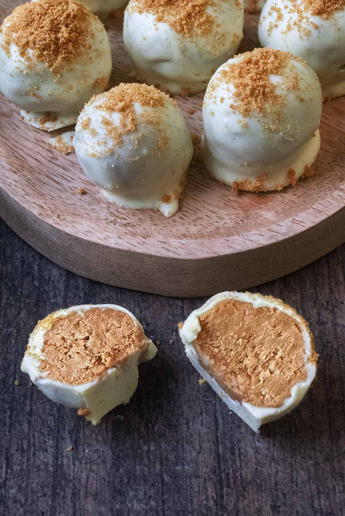 A white chocolate coated truffle cut open and laying in front of other whole truffles.