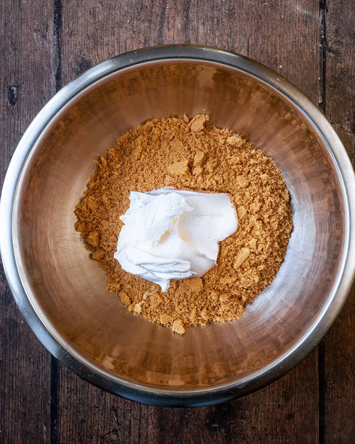 Ginger nut crumbs in a mixing bowl wit ha large dollop of cream cheese.