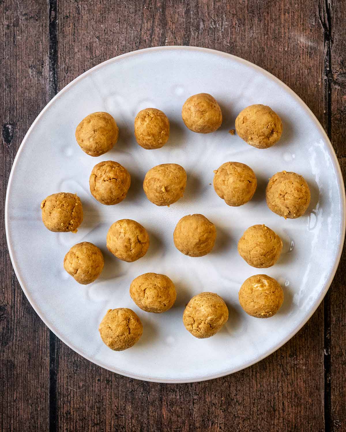 The dough rolled into small balls on a round white plate.