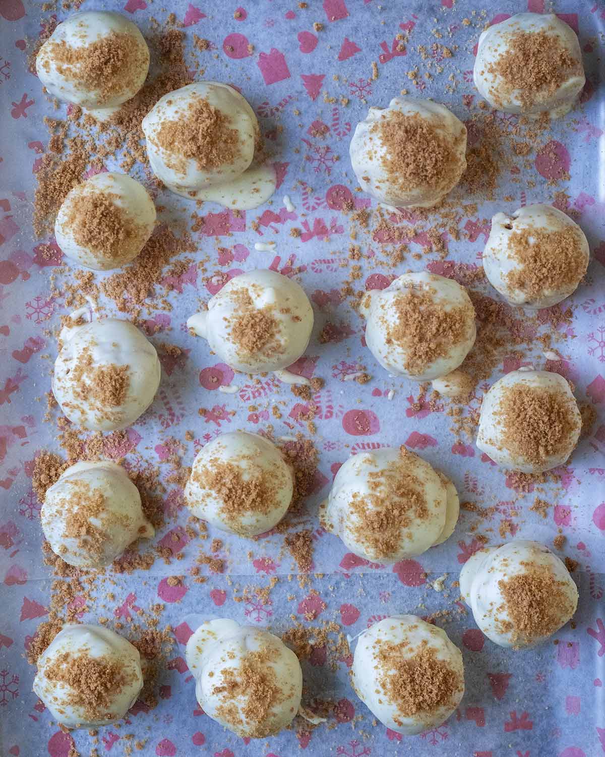 White chocolate covered truffles on Christmas patterned paper.