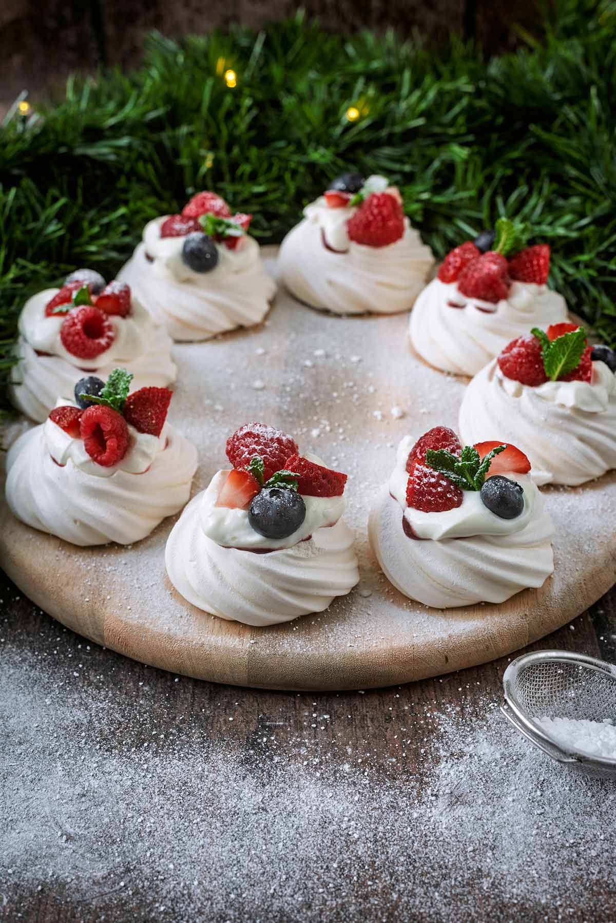 Eight mini pavlovas arranged in a ring on a round wooden board.