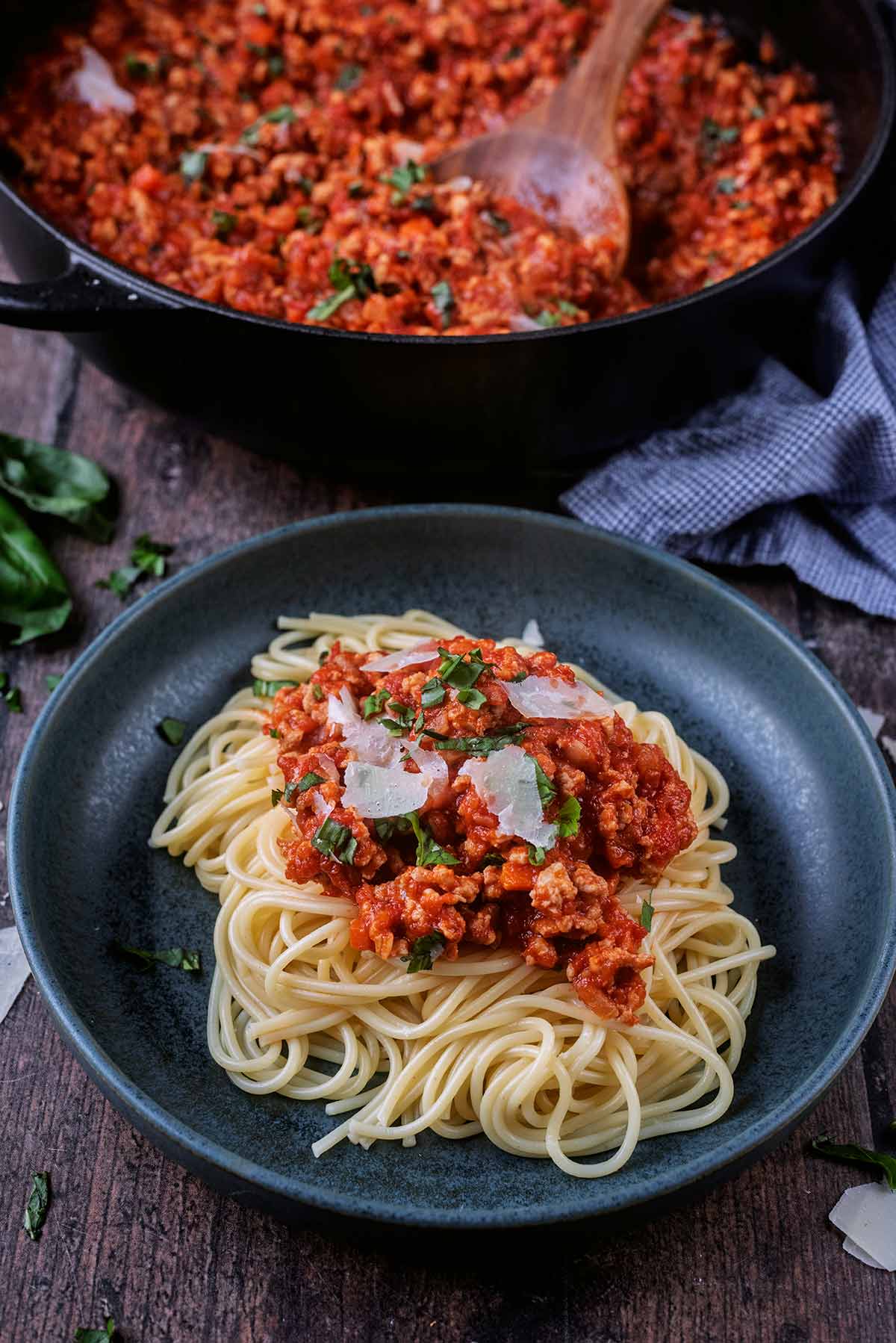 A bowl of spaghetti bolognese in front of a large pan of more bolognese.