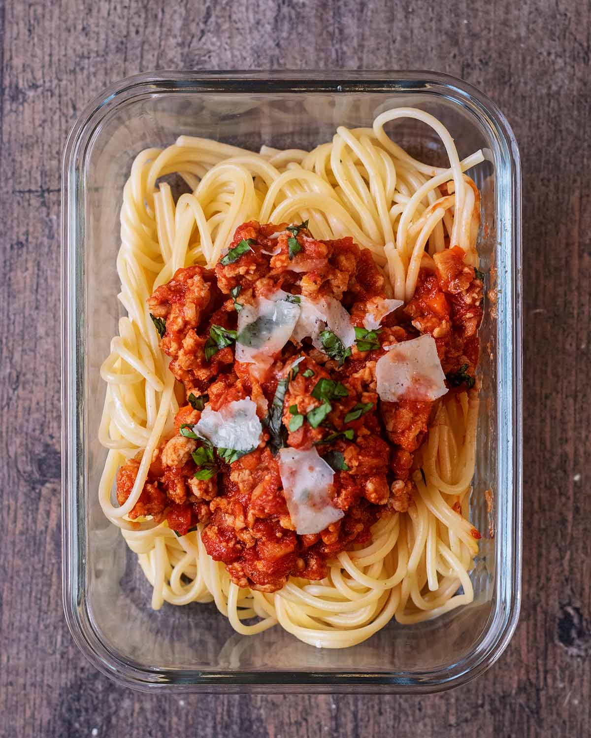Spaghetti bolognese in a glass storage container.